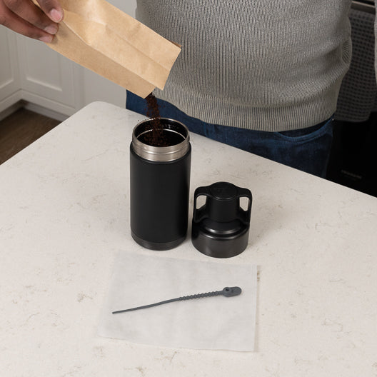 Cold brew grounds being poured into bottom of go brewer